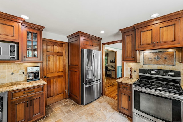 37 Sheffield Ln, Madison, CT 06443 - kitchen featuring stainless steel appliances, light stone countertops, decorative backsplash, stone tile floors, and glass insert cabinets
