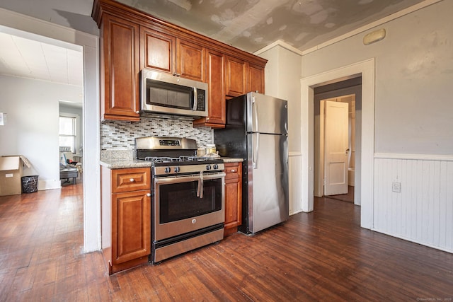 3800 Main St, Stratford, CT 06614 - kitchen featuring stainless steel appliances, dark wood finished floors, brown cabinets, tasteful backsplash, and a wainscoted wall
