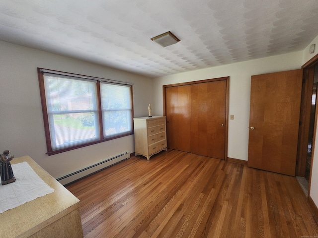 82 Hotchkiss St, Waterbury, CT 06704 - unfurnished bedroom with a baseboard heating unit, light wood finished floors, and a closet
