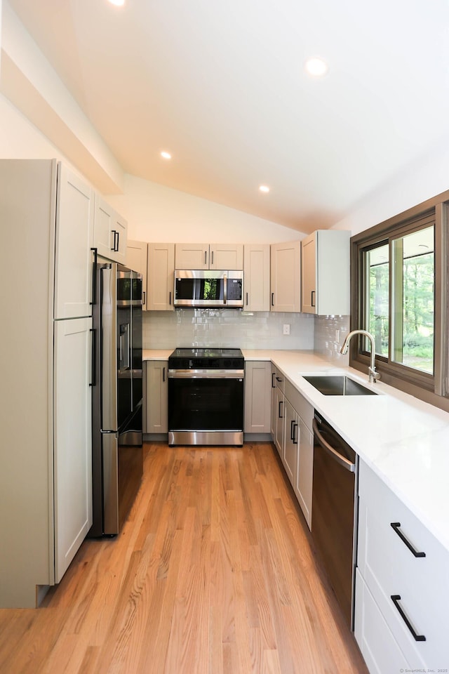 7 Hillcrest Ln, Weston, CT 06883 - kitchen featuring appliances with stainless steel finishes, vaulted ceiling, tasteful backsplash, light countertops, and light wood-style floors