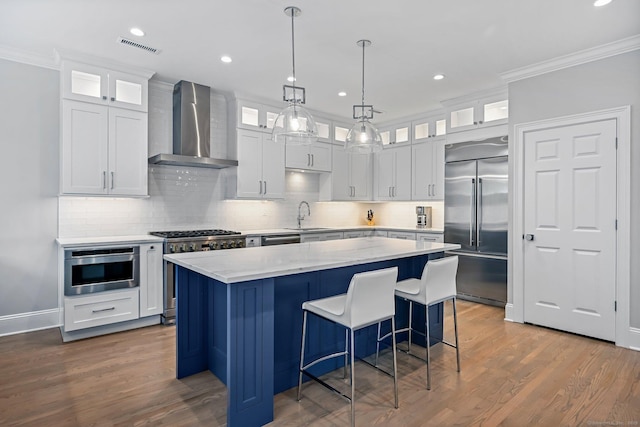 868 S Pine Creek Rd, Fairfield, CT 06824 - kitchen with wall chimney exhaust hood, high quality appliances, a sink, ornamental molding, and a center island