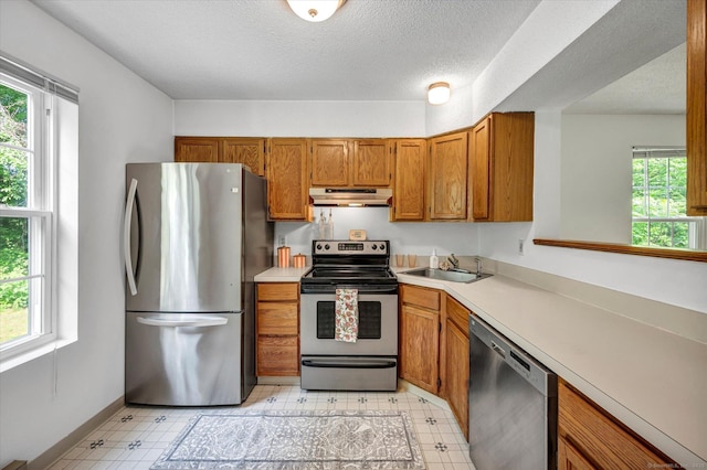 745 Merrow Rd Apt 157, Coventry, CT 06238 - kitchen featuring appliances with stainless steel finishes, under cabinet range hood, light flooring, brown cabinets, and light countertops