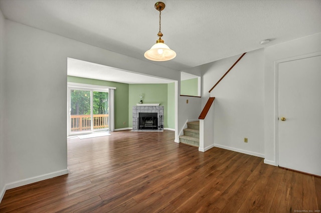 745 Merrow Rd Apt 157, Coventry, CT 06238 - unfurnished living room featuring stairway, wood finished floors, a tiled fireplace, and baseboards