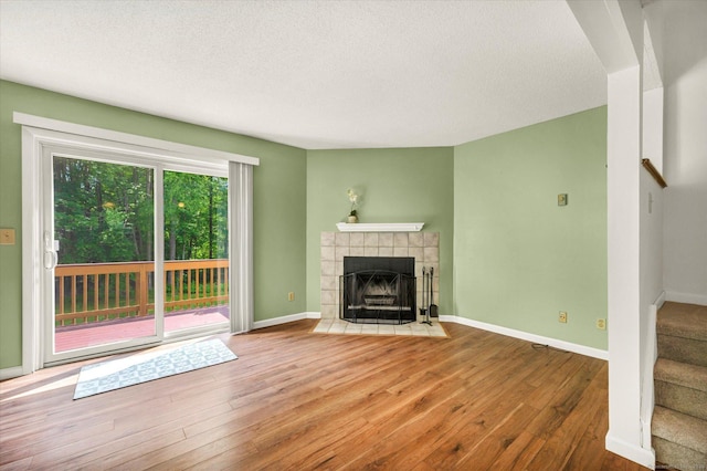 745 Merrow Rd Apt 157, Coventry, CT 06238 - unfurnished living room with stairway, wood-type flooring, a fireplace, a textured ceiling, and baseboards
