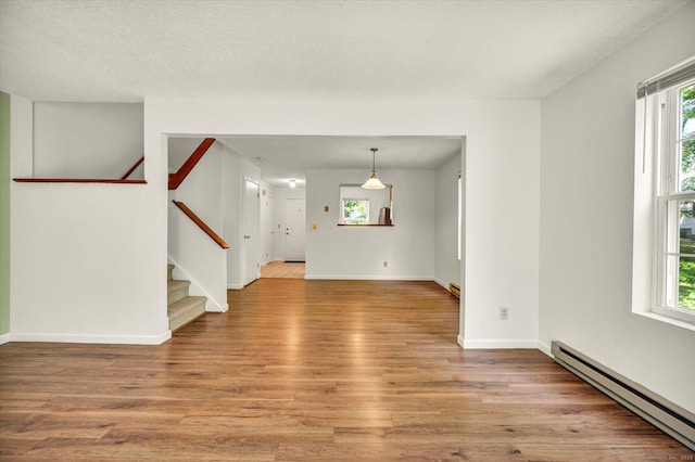 745 Merrow Rd Apt 157, Coventry, CT 06238 - unfurnished living room featuring a baseboard radiator, light wood finished floors, and plenty of natural light