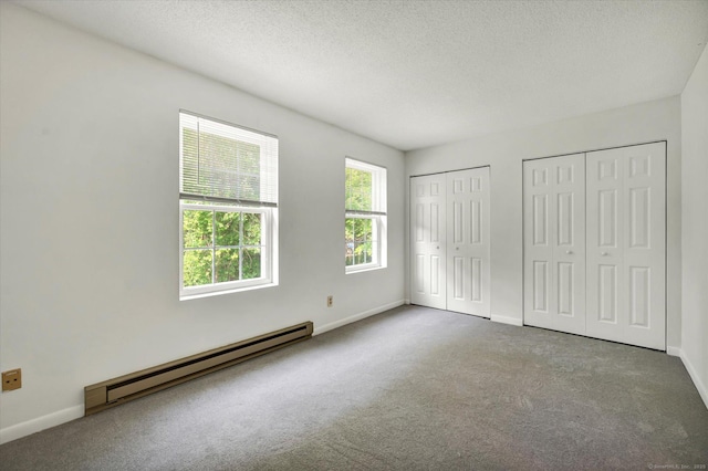 745 Merrow Rd Apt 157, Coventry, CT 06238 - unfurnished bedroom with a baseboard heating unit, two closets, carpet, baseboards, and a textured ceiling