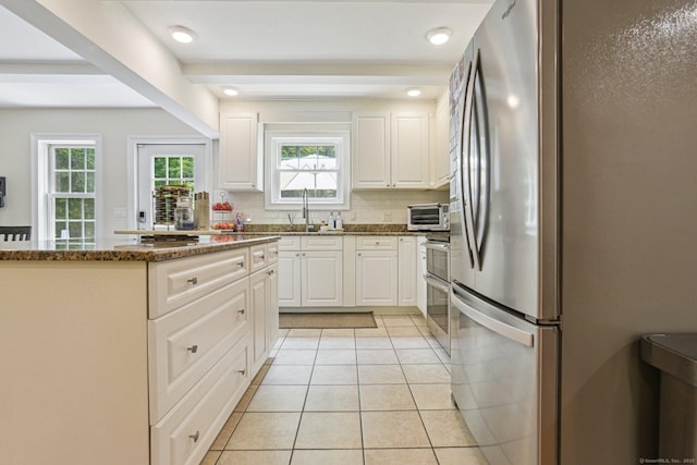 958 Essex Rd, Westbrook, CT 06498 - kitchen with freestanding refrigerator, white cabinets, light tile patterned floors, tasteful backsplash, and dark stone countertops