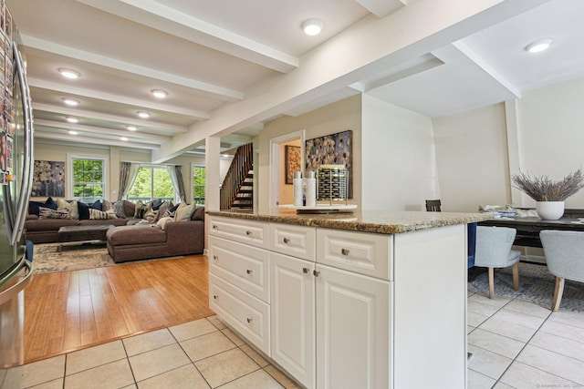 958 Essex Rd, Westbrook, CT 06498 - kitchen with light tile patterned flooring, beamed ceiling, dark stone countertops, a center island, and white cabinets