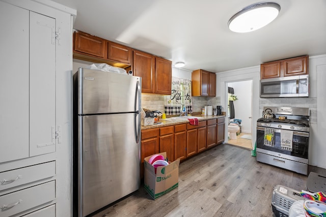 60 Albert St, Torrington, CT 06790 - kitchen with appliances with stainless steel finishes, decorative backsplash, light wood-style floors, brown cabinets, and light countertops