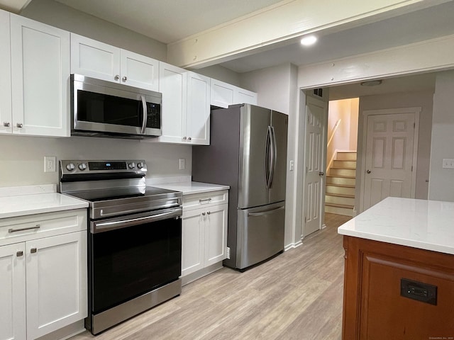 8 Highpoint Ct Unit 8, Woodbury, CT 06798 - kitchen featuring appliances with stainless steel finishes, light wood finished floors, white cabinetry, and light stone counters