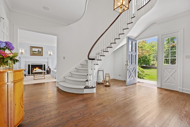66 Stanton Rd, Darien, CT 06820 - foyer with stairs, dark wood-style flooring, a lit fireplace, crown molding, and a chandelier