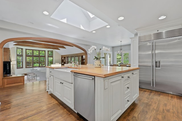 66 Stanton Rd, Darien, CT 06820 - kitchen featuring appliances with stainless steel finishes, arched walkways, recessed lighting, white cabinets, and an island with sink