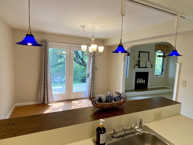 64 Copper Beech Dr Unit 64, Rocky Hill, CT 06067 - kitchen featuring a sink, a textured ceiling, hanging light fixtures, baseboards, and wood finished floors
