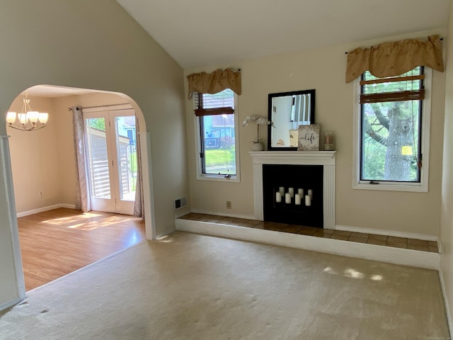 64 Copper Beech Dr Unit 64, Rocky Hill, CT 06067 - unfurnished living room featuring carpet flooring, a chandelier, arched walkways, a fireplace with raised hearth, and baseboards