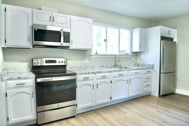 10 Fleming St, Waterbury, CT 06710 - kitchen with stainless steel appliances, a sink, white cabinetry, light wood-style flooring, and light stone counters
