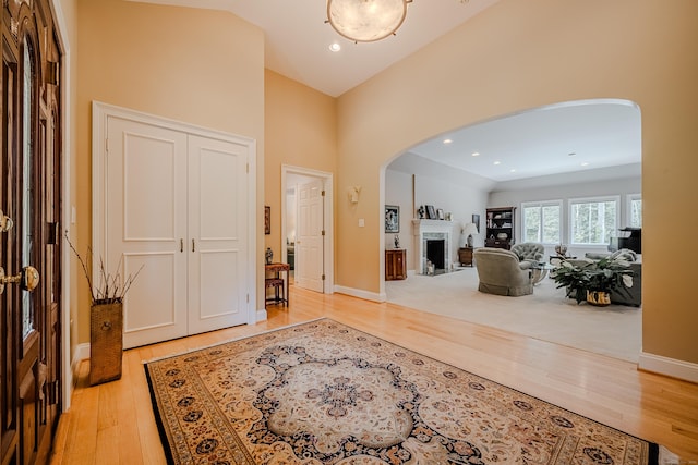 5 Stone Wall Ln, Woodbridge, CT 06525 - foyer entrance with arched walkways, a fireplace, wood finished floors, a high ceiling, and baseboards