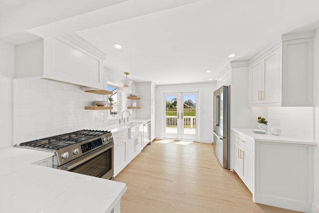 105 Blake Dr, Fairfield, CT 06824 - kitchen featuring appliances with stainless steel finishes, open shelves, backsplash, white cabinets, and light wood-style flooring