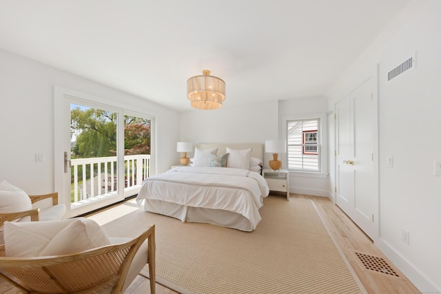 105 Blake Dr, Fairfield, CT 06824 - bedroom with access to outside, multiple windows, light wood-style floors, and a chandelier