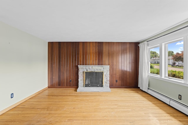 26 Caroldon Rd, Middletown, CT 06457 - unfurnished living room with baseboard heating, light wood finished floors, wood walls, and a stone fireplace