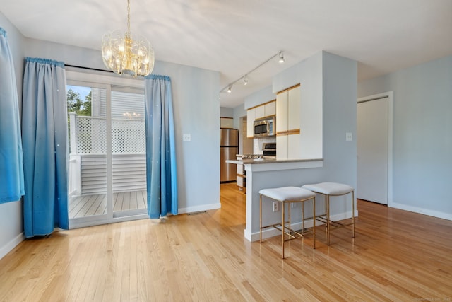 66 Staffordshire Commons Dr Unit 66, Wallingford, CT 06492 - kitchen featuring appliances with stainless steel finishes, light wood-style floors, baseboards, a chandelier, and a kitchen breakfast bar