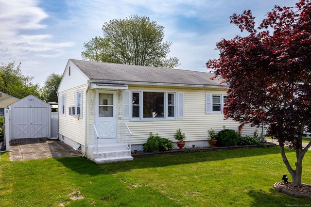 view of front of home with entry steps, a front yard, a storage shed, and roof with shingles