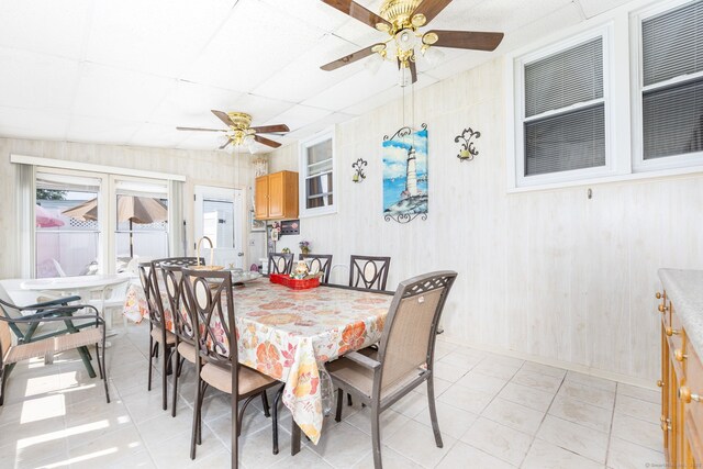 dining room with ceiling fan, light tile patterned floors, and a drop ceiling