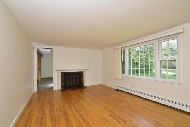 118 Putnam Rd, Pomfret, CT 06259 - unfurnished living room with baseboard heating, light wood-type flooring, healthy amount of natural light, and a brick fireplace
