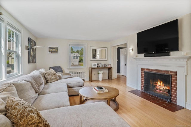 185 Lovers Ln, Fairfield, CT 06824 - living room featuring radiator, light wood-style flooring, and a brick fireplace