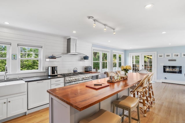 185 Lovers Ln, Fairfield, CT 06824 - kitchen featuring extractor fan, range with two ovens, butcher block countertops, light wood-style floors, and plenty of natural light