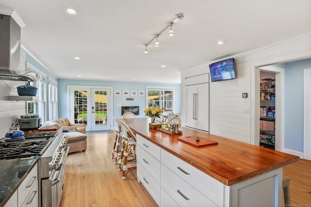185 Lovers Ln, Fairfield, CT 06824 - kitchen with butcher block counters, paneled built in refrigerator, open floor plan, a kitchen bar, and white cabinets