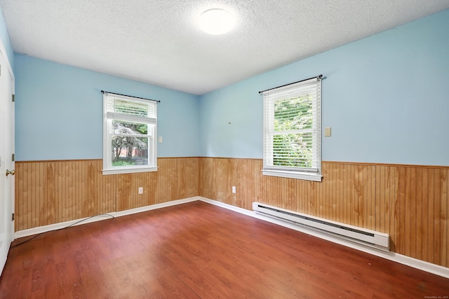 26 Paula Rd, East Haddam, CT 06423 - spare room featuring baseboard heating, a wainscoted wall, wood finished floors, wood walls, and a textured ceiling