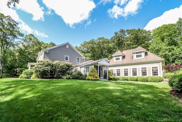 view of front of house with a front yard and view of wooded area
