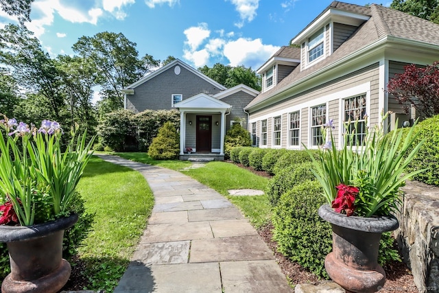 view of front facade featuring roof with shingles and a front lawn