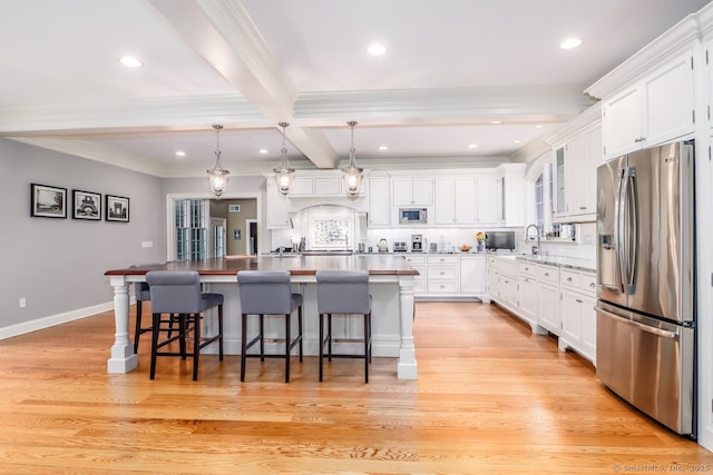 kitchen featuring appliances with stainless steel finishes, beam ceiling, white cabinetry, an island with sink, and crown molding