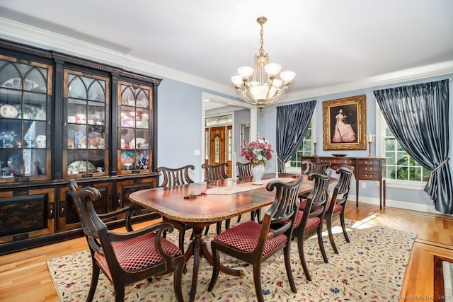 dining room featuring a chandelier, crown molding, light wood-style floors, and baseboards