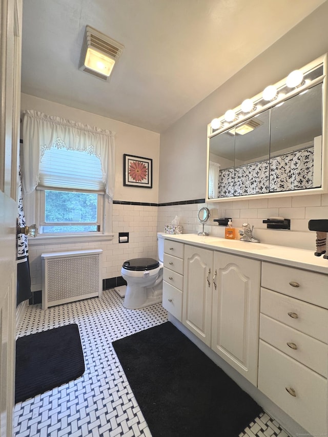 155 Harding St, New Britain, CT 06052 - bathroom with radiator heating unit, tile walls, vanity, wainscoting, and tile patterned floors