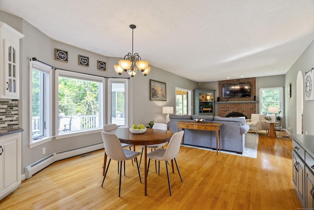 109 Andrew Dr, Canton, CT 06019 - dining space featuring a baseboard heating unit, light wood-type flooring, a brick fireplace, and healthy amount of natural light