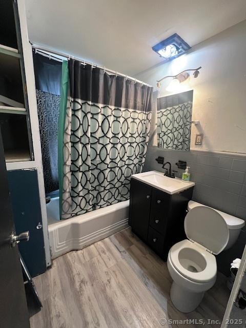 201 Lewis St, Bridgeport, CT 06605 - full bathroom featuring tile walls, shower / bathtub combination with curtain, toilet, wood finished floors, and vanity