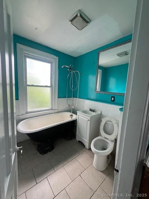 201 Lewis St, Bridgeport, CT 06605 - bathroom featuring a soaking tub, vanity, wainscoting, toilet, and tile walls