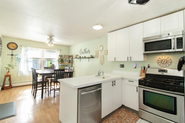 47 Pebble Dr, Newington, CT 06111 - kitchen with appliances with stainless steel finishes, a peninsula, white cabinetry, light countertops, and a textured ceiling