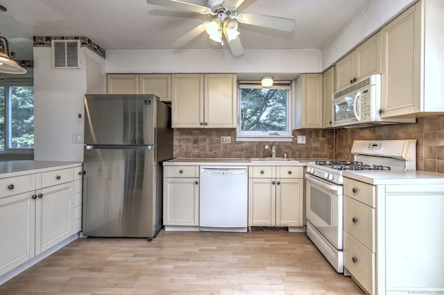 269 Captain Thomas Blvd Unit 12, West Haven, CT 06516 - kitchen featuring white appliances, a sink, light wood-style flooring, light countertops, and backsplash