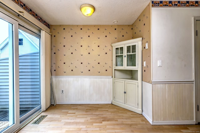 269 Captain Thomas Blvd Unit 12, West Haven, CT 06516 - unfurnished dining area with wainscoting, light wood finished floors, a textured ceiling, and wallpapered walls