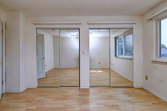 269 Captain Thomas Blvd Unit 12, West Haven, CT 06516 - unfurnished bedroom with light wood-style floors, multiple windows, baseboards, and two closets