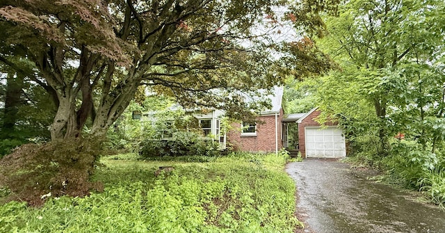 37 Thorpe Ave, Meriden, CT 06450 - obstructed view of property featuring an attached garage, asphalt driveway, and brick siding