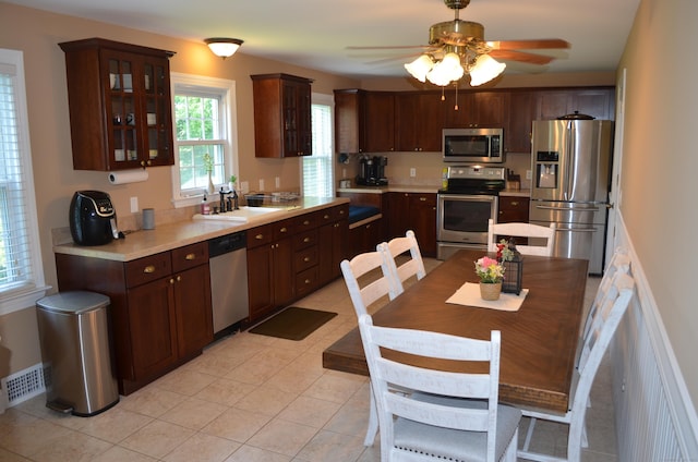 55 Cloudland Rd, North Haven, CT 06473 - kitchen with appliances with stainless steel finishes, light countertops, dark brown cabinetry, ceiling fan, and glass insert cabinets