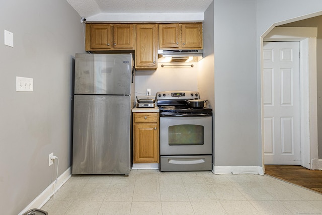 72 Beech St, Bristol, CT 06010 - kitchen with appliances with stainless steel finishes, under cabinet range hood, brown cabinetry, arched walkways, and a textured ceiling