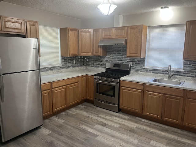 20 Cossett St, Waterbury, CT 06704 - kitchen featuring appliances with stainless steel finishes, under cabinet range hood, a textured ceiling, backsplash, and light wood-style flooring