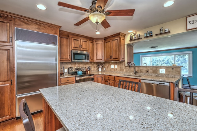 17 Farmstead Ln, West Hartford, CT 06117 - kitchen with appliances with stainless steel finishes, a sink, brown cabinetry, light stone counters, and ceiling fan