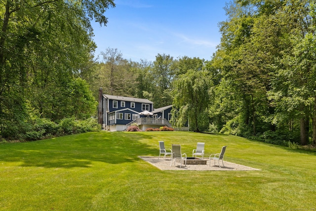 43 Debi Cir, Colchester, CT 06415 - view of grassy yard with a fire pit, a deck, a wooded view, and a patio