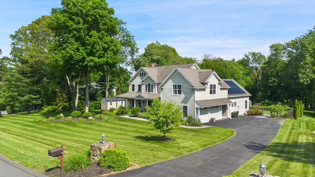11 Delno Dr, Danbury, CT 06811 - view of front of house with asphalt driveway, solar panels, a front yard, a garage, and a chimney